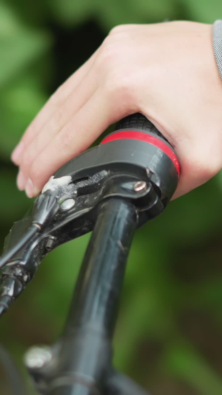 primer plano de alguien en tela de hash, agarrando el manillar de una bicicleta mientras viaja a lo largo de un camino escénico rodeado de exuberante vegetación con el fondo ligeramente borroso