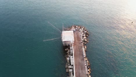 Aerial-view-over-a-trabucco,-traditional-fishing-machine,-on-the-italian-seashore,-at-sunset