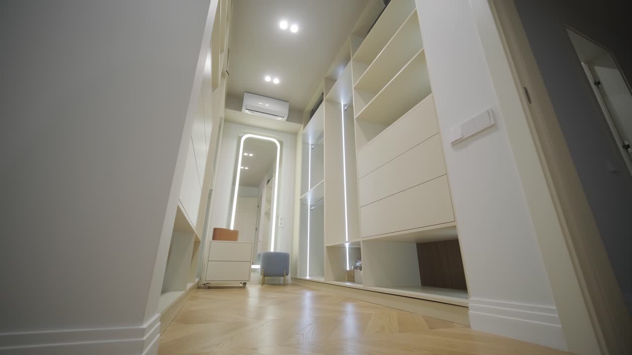 una sala de vestuario contemporánea iluminada con iluminación suave, con armarios incorporados y un espejo de longitud completa, colocado en un elegante piso de madera