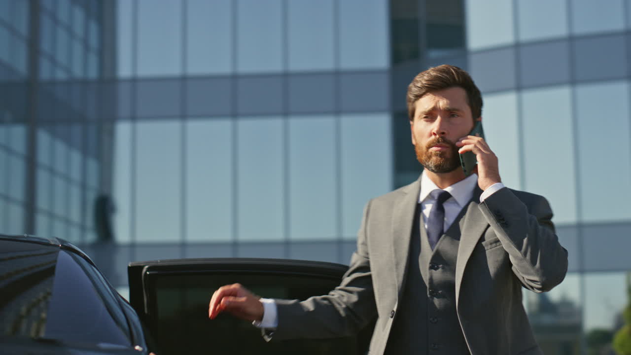un empresario exitoso que obtiene un coche de clase premium hablando por teléfono móvil de cerca.
