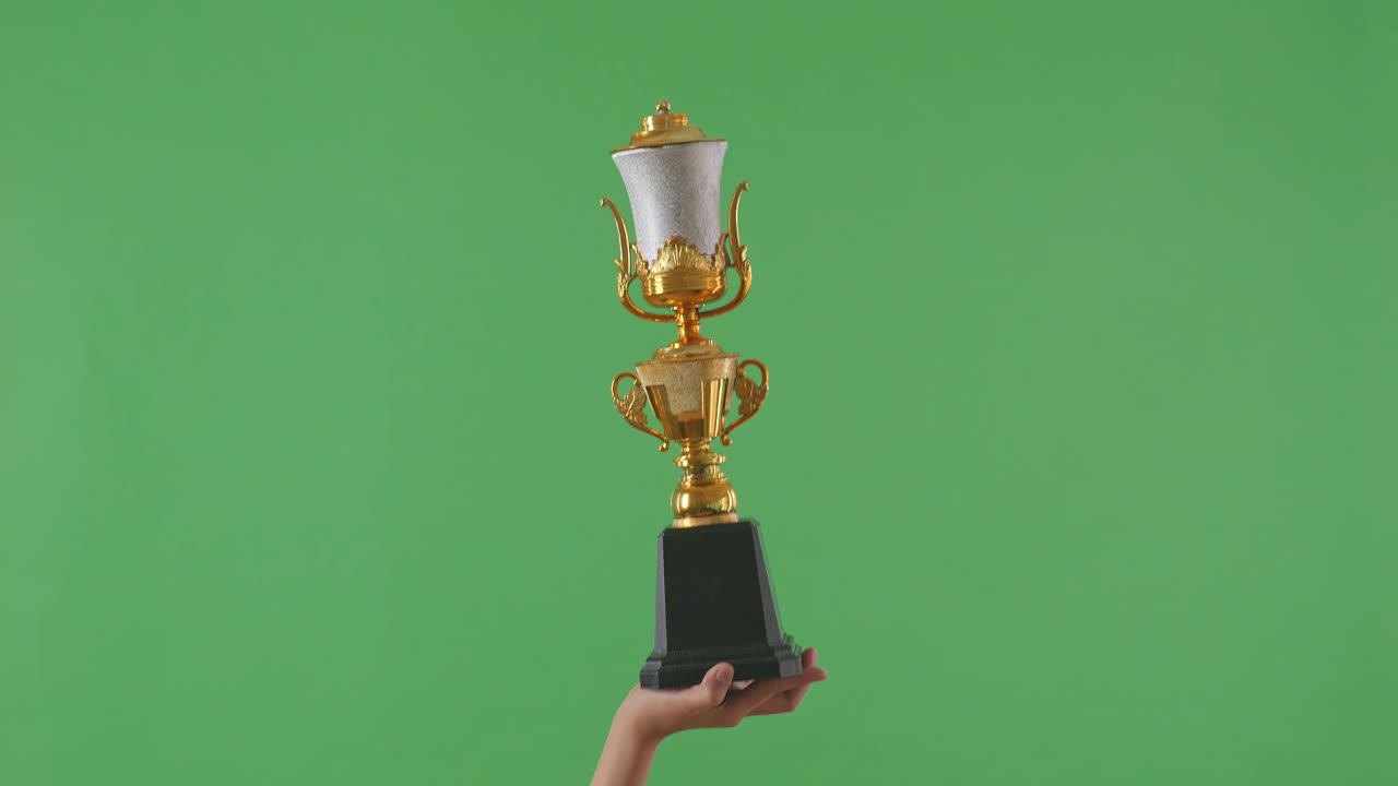 las manos levantadas de una mujer están sosteniendo un trofeo. fondo de pantalla verde