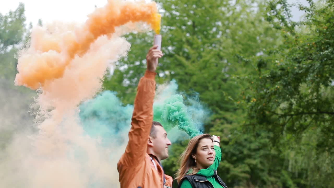 Young couple in love standing with color smoke bomb