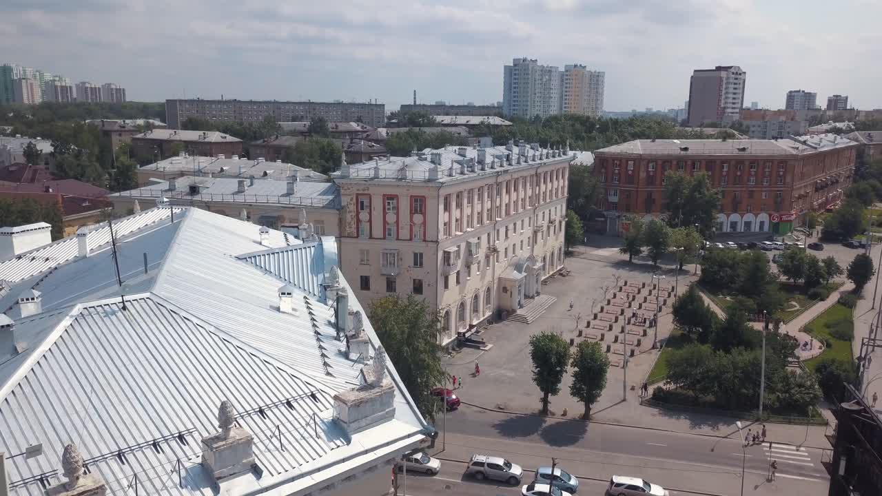 вид на улицу с зданиями, парком и машинами