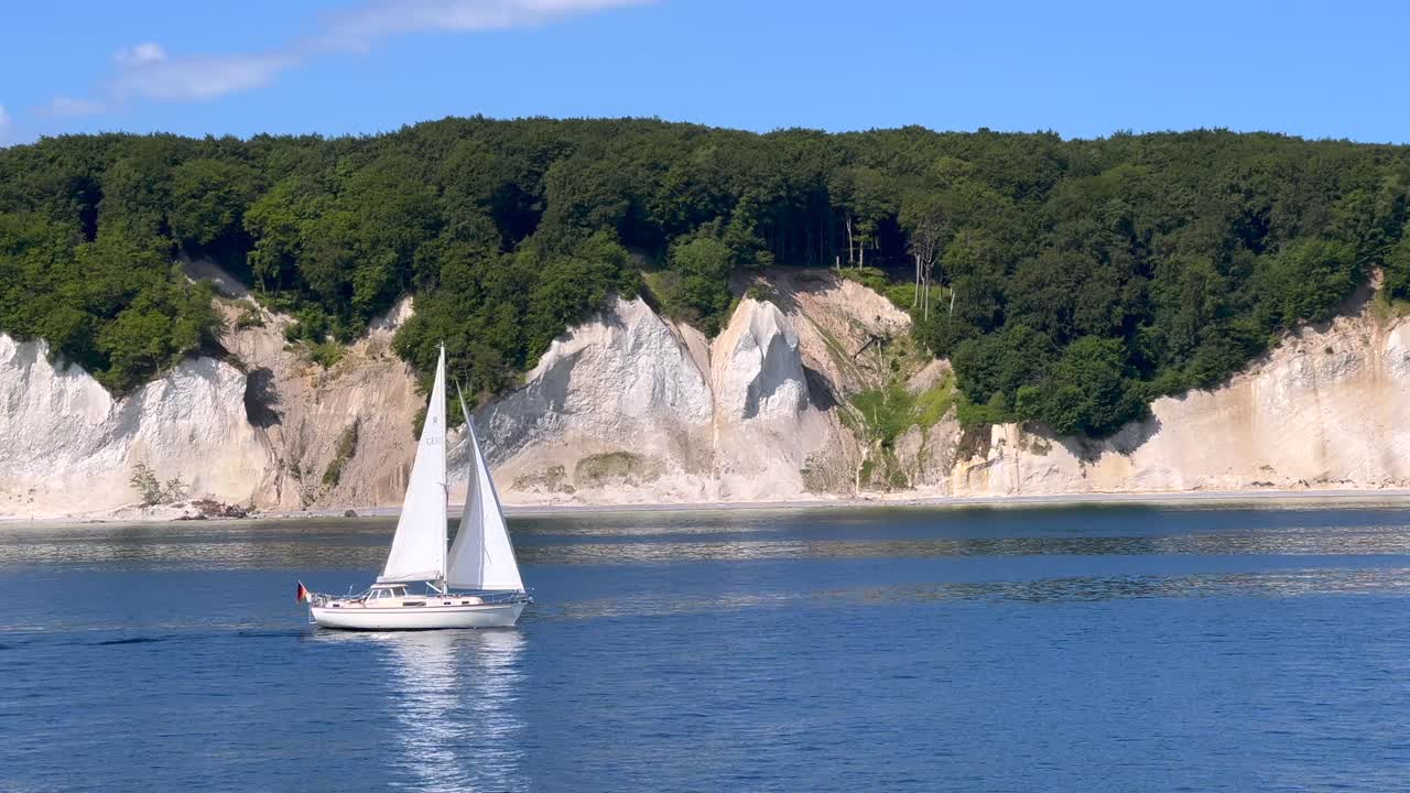 The very famous chalk cliffs of the R&uuml;gen Island in Germany, viewed from the baltic sea, with a small passing sailboat