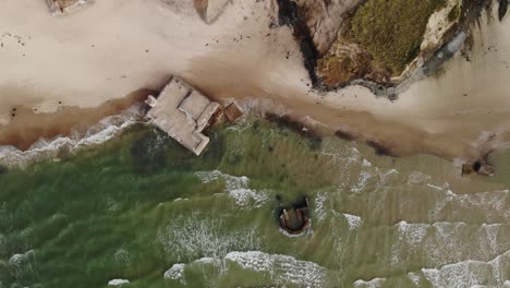 aerial top down with no movement of old german bunkers in the water slowly eroding by the ocean while seagulls fly around at the danish west coast