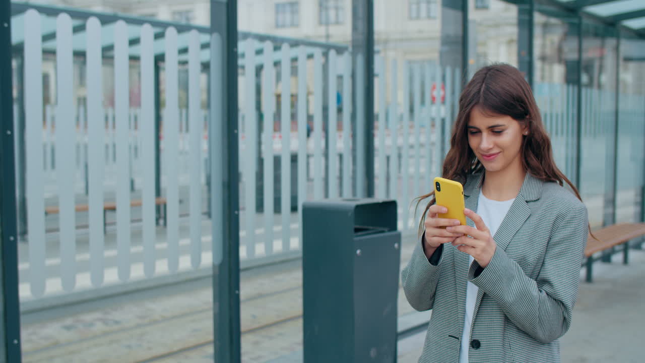 Young Woman Using Smartphone at a Public Transport Stop