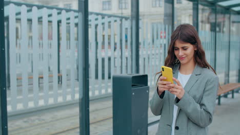young woman using smartphone at a public transport stop