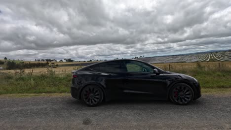 black ev parked near solar panels under cloudy sky