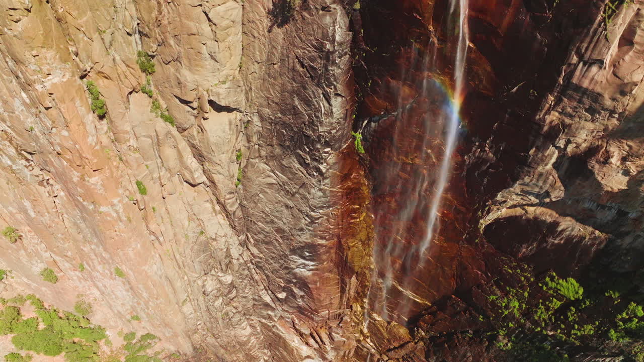 Almost dried waterfall with water spraying in the wind and creating rainbow. Cliffs of Yosemite National Park, California, USA on sunny day.