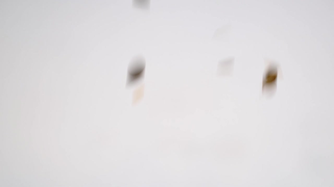 Gold confetti falling against a white background