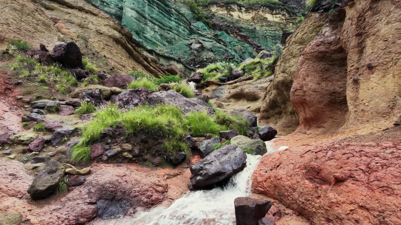 Vakker utsikt over de unike fargerike fjellene i Los Azulejos de Veneguera. En bekk renner gjennom de geologiske formasjonene etter en storm