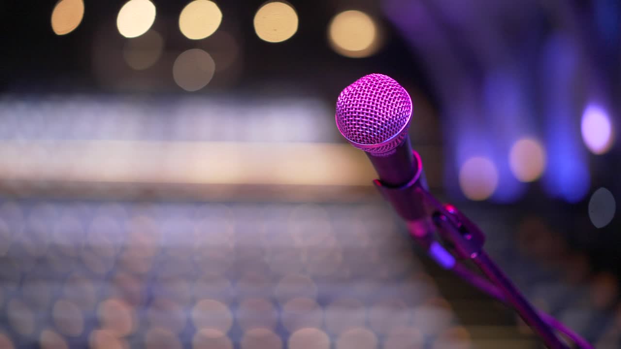 Microfono inutilizzato sul palco di un teatro vuoto, sensazione di ansia da palcoscenico.