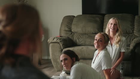 over-the-shoulder view of bride as her bridesmaids smile laugh reacting to look