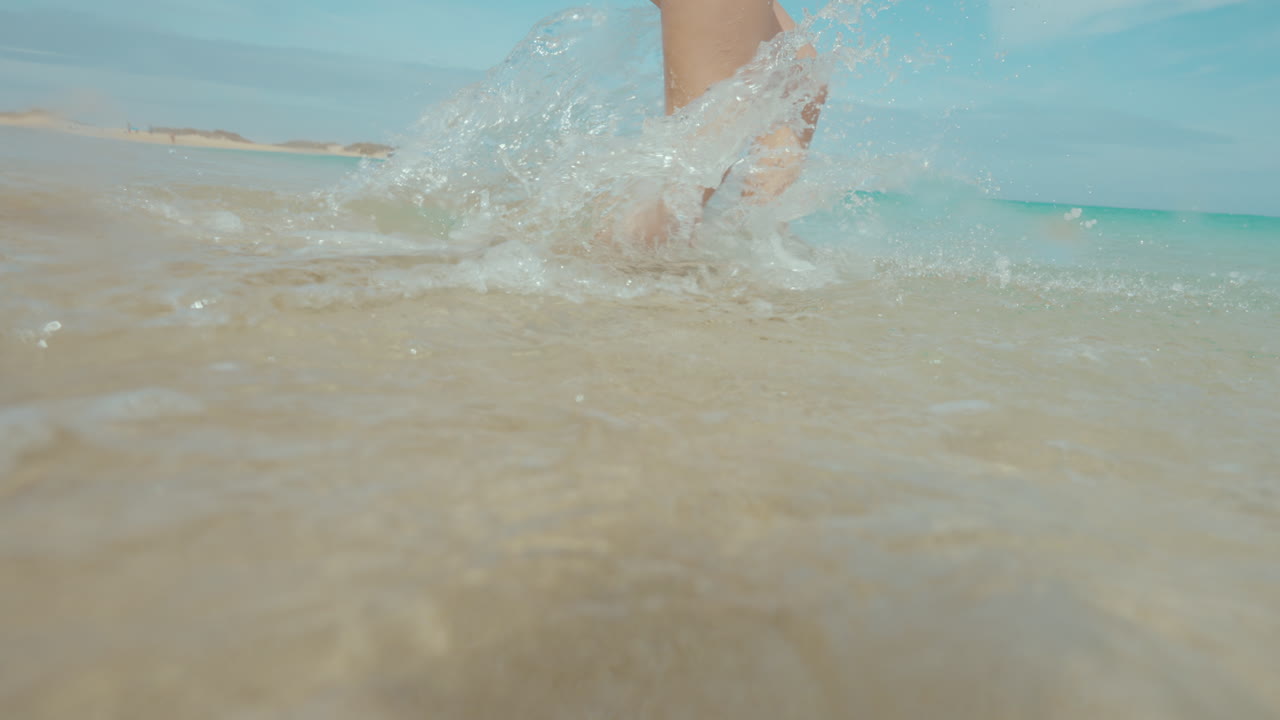 Woman Running Through Shallow Water on a Beach