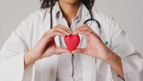 Video-of-biracial-female-doctor-holding-heart-on-white-background