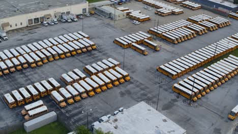 Drone-view-of-row-of-yellow-school-buses-in-large-parking-lot