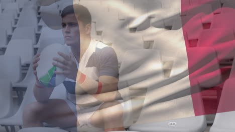 animation of french flag waving over caucasian male rugby player sitting and holding a ball