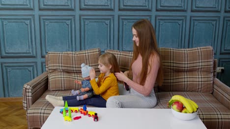 Madre-Cuidando,-Cepillando-El-Pelo-De-Su-Hija-En-La-Sala-De-Estar,-Niño-Jugando-Con-Muñeca-De-Juguete