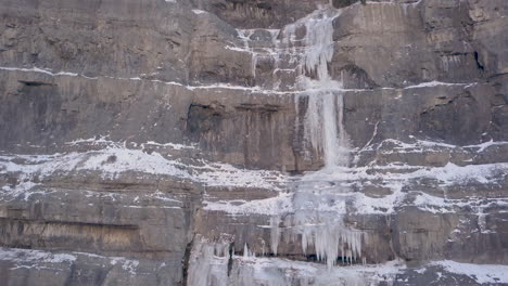 Una-Cascada-Congelada-A-Lo-Largo-De-Un-Acantilado-De-Corte-En-Una-Escena-De-Invierno---Panorámica-Hacia-Arriba