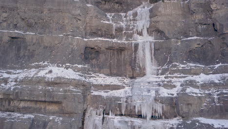 una cascada congelada a lo largo de un acantilado de corte en una escena de invierno - panorámica hacia arriba