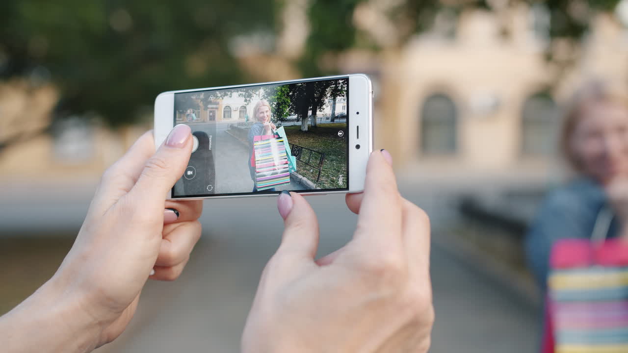 Woman taking a picture of her friend with shopping bags