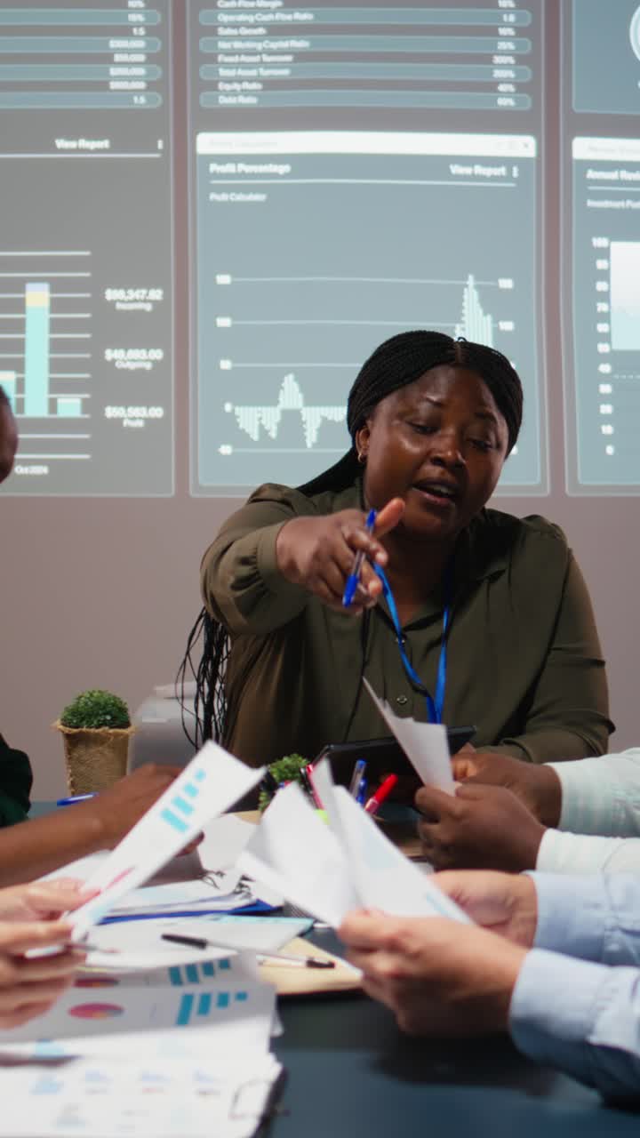 Vertical Video Business partners examining annual sales reports in corporate meeting
