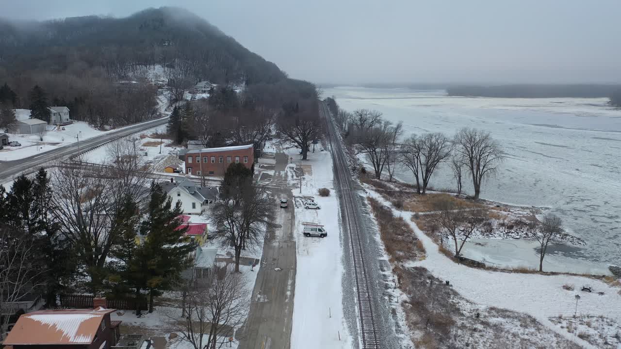 Snowy City Street Scene with Parking Lot and Train Tracks