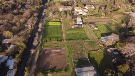 Una-Filmación-Aérea-Orbital-Dinámica-De-La-Puesta-De-Sol-En-Una-Granja-De-Hortalizas-En-Agronomía,-Buenos-Aires