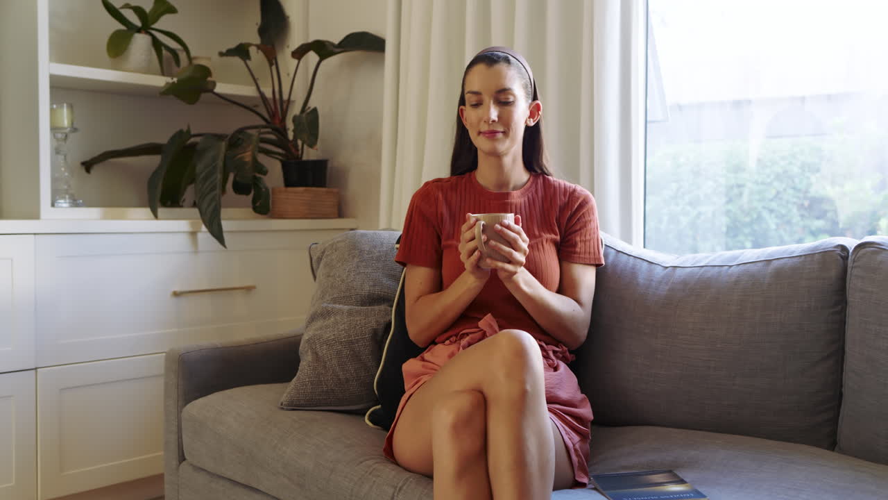 Woman relaxing on sofa, holding coffee cup, enjoying peaceful moment at home