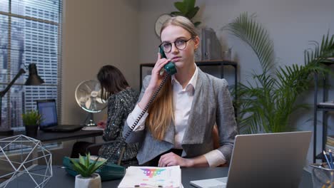 Annoyed-young-businesswoman-talking-on-retro-telephone-call-irritated-voice-dissatisfied-with-work