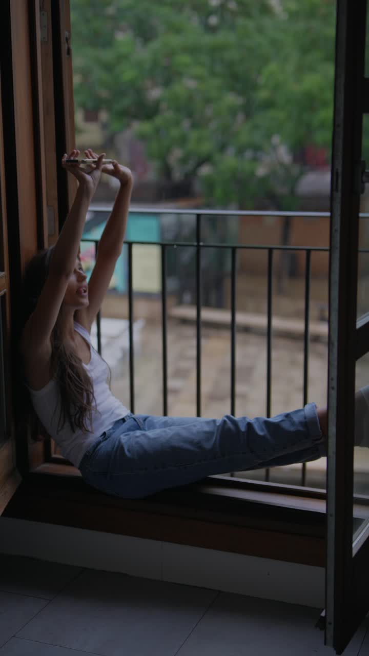 un adolescente tomando una selfie en un balcón en un día de lluvia