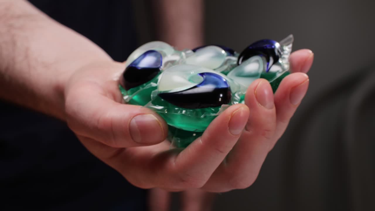 Hand holding laundry detergent pods