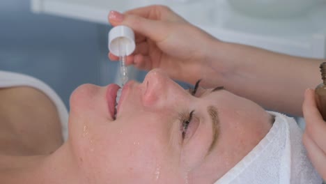 a beautiful woman is lying on a couch at a reception by a beautician. the doctor makes beauty injections to the lips. vertical video