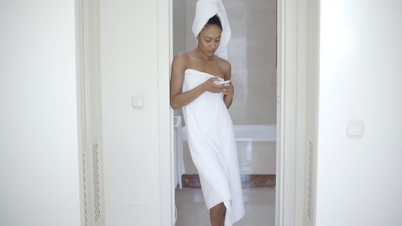 Donna che scrive messaggi al cellulare in bagno e sorride