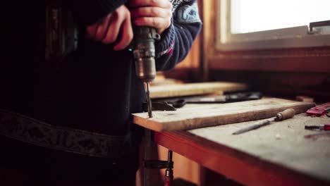 man using a cordless driller to make hole on plank then used a hand saw