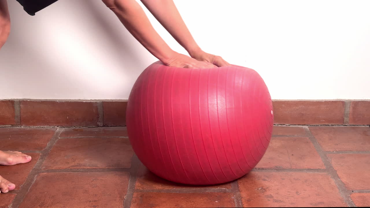 Person's Hands Pressing and Deforming a Red Exercise Ball