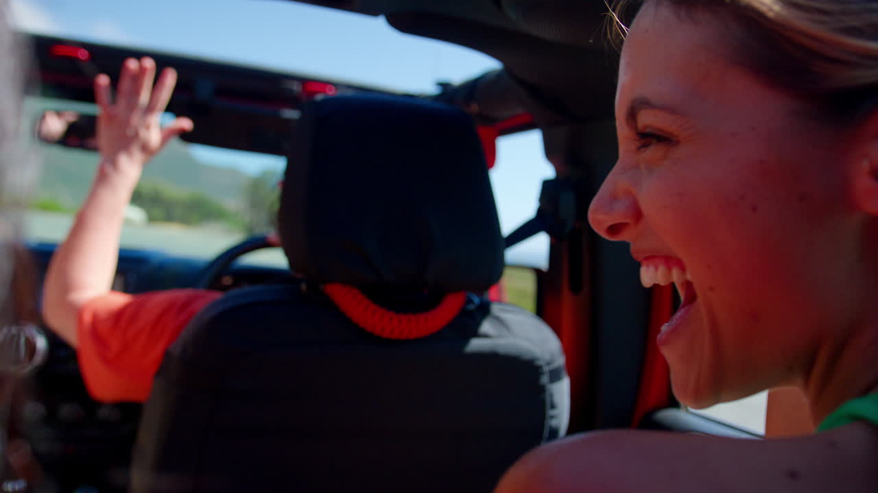 웃고 있는 여성 친구 들 의 그룹 이 도로 여행 에 있는 오픈 탑 자동차 의 선루프 를 통해 손 을  ⁇ 고 있다