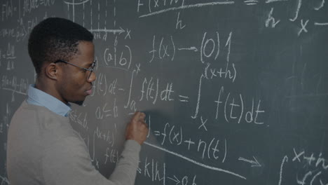 man writing equations on a chalkboard