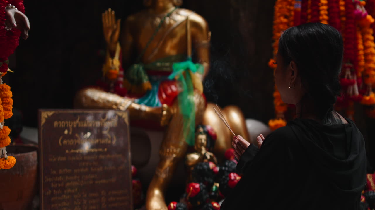 Mulher orando em um templo budista com incenso