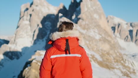 enfoque al hombre parado frente a impresionantes picos montañosos