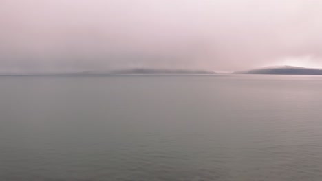 Scenic-aerial-view-above-breathtaking-Iceland-coastline-with-background-mountains-on-overcast-winter-sunset,-drone-flying-forward