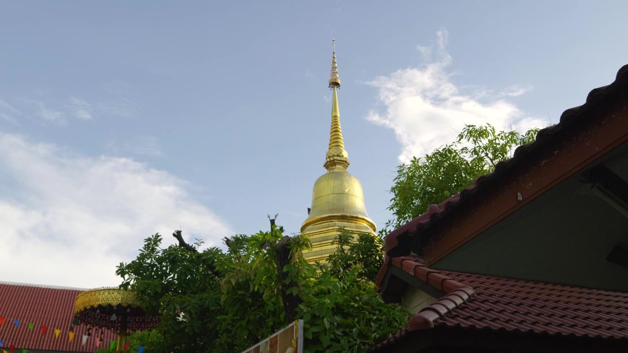 Inquadratura cinematografica che rivela uno Stupa dorato contro il cielo blu in Thailandia.