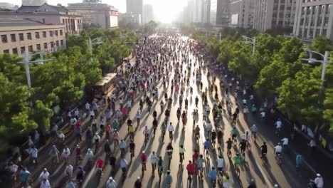 aerial view of a busy city street filled with cyclists and pedestrians at sunset, showcasing urban life and recreational activity in an urban environment