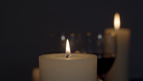 candle being lit with match with a glass of wine and burning candle on background