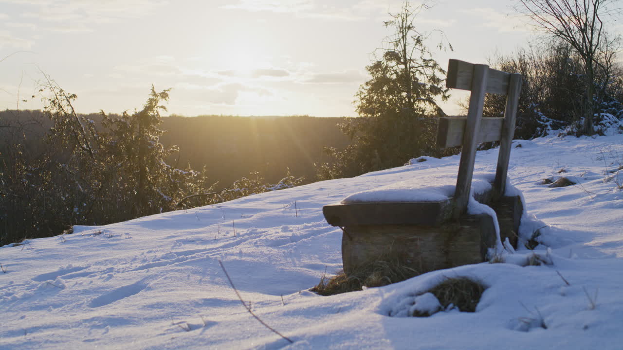 아름다운 일몰 동안 작은 언덕에 눈 덮인 벤치의 정적 중간 와이드 샷