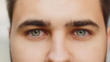 Extreme-close-up-macro-portrait-of-young-face,-bearded-man's-eyes-looking-at-camera,-smiling