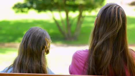 mother and daughter sitting together on a park bench