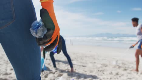 grupo diverso de amigas poniendo basura en bolsas de basura en la playa