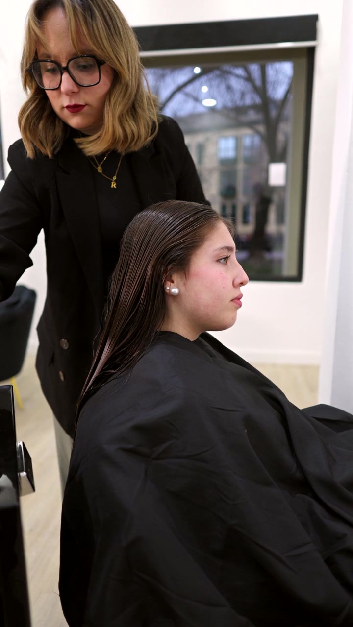Parrucchiere professionista che applica la tinta per capelli a una cliente in un salone