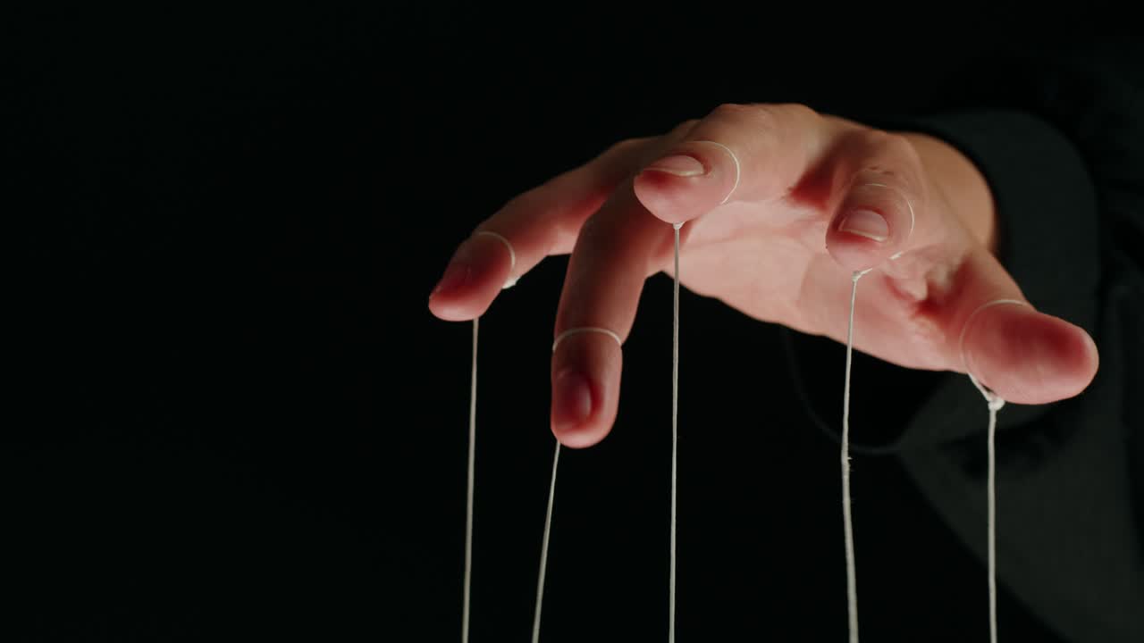 Close-up of Human Hand Manipulated by Puppet Strings